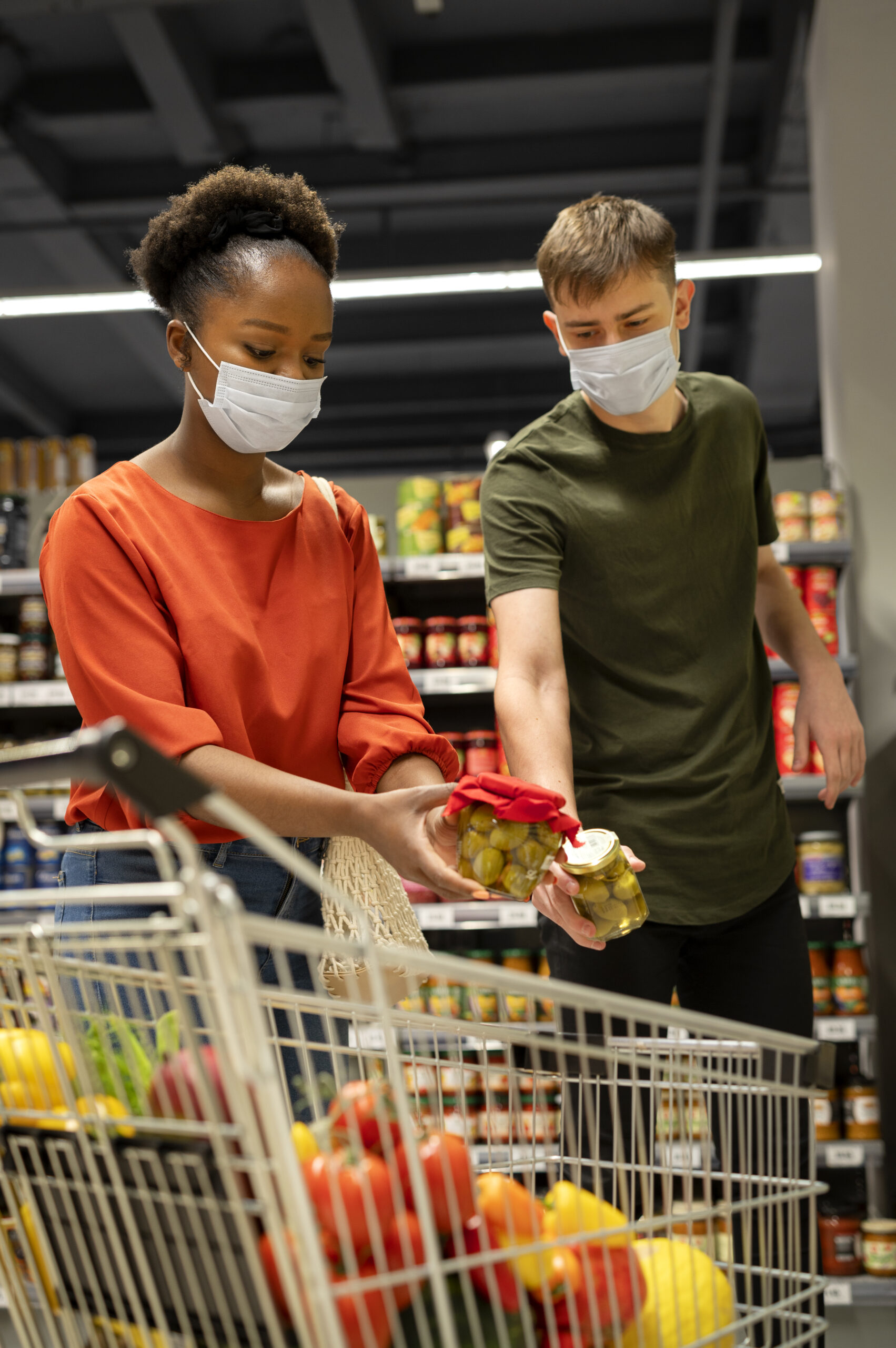 man woman with medical masks out grocery shopping with shopping cart